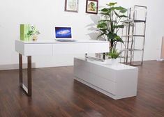 a white desk with a laptop on it and a potted plant in the corner