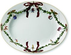 a white plate with christmas decorations on the rim and red ribbon around the edge,