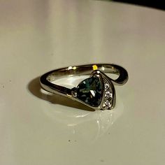 a ring with a green diamond on it sitting on top of a white countertop