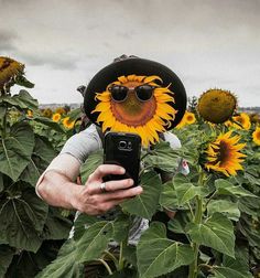 a person taking a selfie in front of sunflowers with sunglasses and a hat