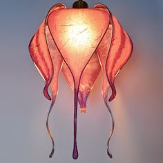 a pink lamp hanging from the side of a wall with an artistic design on it