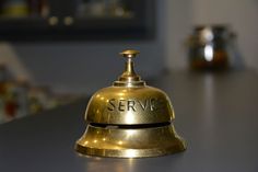 a brass bell with the word service on it sitting on a table in a kitchen