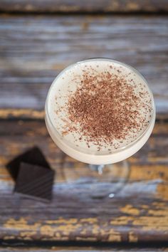 A coupe cocktail glass filled with mudslide cocktail and garnished with grated chocolate, standing on a yellow brown wooden table, with 2 pieces of chocolate next to it. Mudslide Recipe, Cocktails Made With Vodka, Winter Drink, Mudslide, Irish Cream Liqueur, Shakes Drinks, Cream Liqueur, Winter Drinks