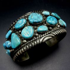 "VINTAGE NAVAJO BRACELET DESCRIPTION: This impressive cuff features 21 specimens of blue Arizona turquoise.. The gemstones are secure in smooth bezel, on a foundation of heavy gauge vintage sterling silver. Plump applied raindrops punctuate the turquoise cabochons and chisel stamped designs frame the edges. This fine bracelet will be a cherished addition to your collection of fine vintage Native American jewelry. MEASUREMENTS: Interior of the cuff measures 5 7/8\" with an additional 1 1/4\" non- Unique Blue Cuff Bracelets, Blue Unique Cuff Bracelet For Formal Occasion, Unique Blue Cuff Bracelet For Formal Occasions, Blue Cuff Bracelets, Blue Collectible Cuff Bracelet Bangle, Vintage Turquoise Bangle Cuff Bracelet, Handmade Turquoise Vintage Cuff Bracelet, Vintage Turquoise Bangle As A Gift, Vintage Blue Cuff Jewelry