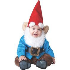 a baby wearing a santa hat and sitting on the ground with his hands in his pockets