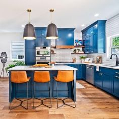 a kitchen with blue cabinets and two yellow chairs in the center island, surrounded by wood flooring