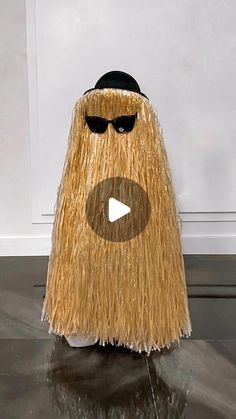 a fake mop with sunglasses and a hat on it's head is shown in front of a white wall