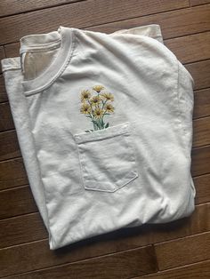 This item is made to order. Please allow 1 week for processing before the item is shipped. State of Blossoms crafts machine embroidered shirts in Bel Air, MD. Please send me a message for custom orders. I'd love to work with you to design something you love. **SIZES ARE UNISEX** Made using 100% ringspun cotton, the Comfort Colors t-shirt is a high-quality heavyweight pocket t-shirt. Preshrunk to prevent unwanted shrinkage, soft-washed for added comfort, and sewn using garment-dyed fabric. White Crew Neck T-shirt With Floral Applique, Embroidered Pocket Tees, White Short Sleeve T-shirt With Floral Applique, White Floral Applique Crew Neck T-shirt, Casual Cotton Shirt With Machine Embroidery, Multicolor Embroidered Cotton Shirt, Embroidered Cotton T-shirt, Spring Cotton Shirt With Embroidered Text, Spring White T-shirt With Custom Embroidery