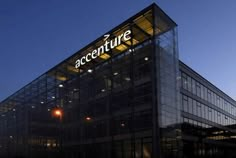 an office building with the word accenture lit up at night