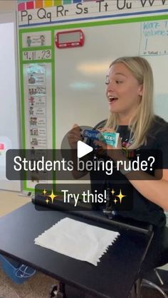 a woman sitting in front of a whiteboard holding a piece of paper and talking to someone