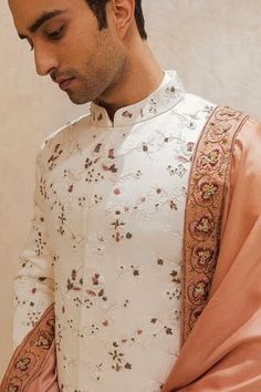 White linen silk sherwani featuring fine tone on tone embroidered floral motifs highlighted with zari work. Comes with kurta, pant and stole. Components: 4 Pattern: Embroidered Type Of Work: Zari Neckline: Mandarin Collar Sleeve Type: Full Fabric: Linen Silk Color: White Other Details:  Hidden placket Tone on tone embroidery Contrast stole Occasion: Groom,Wedding - Aza Fashions Manpreet Toor, Jatin Malik, White Sherwani, Embroidered Sherwani, Dhoti Pants, Fashion Design Portfolio, Haldi Ceremony, Indian Man, Old Rose