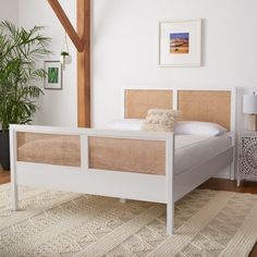 a white bed sitting on top of a wooden floor next to a plant in a bedroom