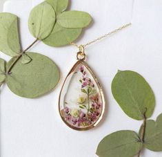 "A beautiful and unique Botanical inspired terrarium necklace with gorgeous real pressed Yorkshire Heather picked on the moors, gorgeous white and pink gypsophila and folliage.   Beautiful lilac flowers in a teardrop pendant.  For someone who needs to wish, for wishes to be granted and for communicating with the spirit world.  The flower is encapsulated in a crystal clear Resin which is Non-toxic, No VOCs, No fumes, No solvents, Non-flammable, Non-hazardous, No BPA.  The necklace chain is gold plated solid brass or stamped 14k gold filled chain as shown in last photo. This chain is much more long lasting and delicate.  The pendant is 1 inch in width and length.  A cute and eco friendly gift for yourself or a loved one. 🌼 So someone you love can bring spring with them wherever they go 🌼 Pink Bohemian Jewelry With Pressed Flowers, Bohemian Pink Jewelry With Pressed Flowers, Nature-inspired Teardrop Pendant Necklace For Gifts, Nature-inspired Teardrop Pendant Necklace As Gift, Nature-inspired Necklace With Adjustable Chain For Gift, Nature-inspired Jewelry With Adjustable Chain As Gift, Nature-inspired Necklace With Adjustable Chain As Gift, Unique Teardrop Necklace For Gift, Nature-inspired Rose Gold Pendant Necklace