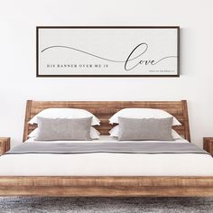 a bedroom with a bed, nightstands and a framed love sign on the wall