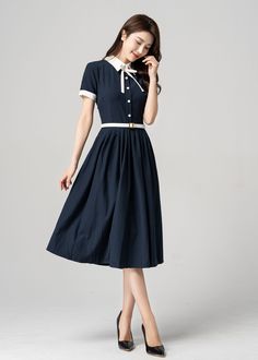 "Step back in time with this gorgeous vintage navy blue short-sleeved shirt dress. The classic design features a flattering cut and is perfect for any occasion. The dress can be dressed up with heels and accessories for a formal event or dressed down with flats for a more casual look. The short sleeves make it perfect for warmer weather, while the navy blue color gives it a timeless appeal. DETAIL * Made of cotton blend * Has No pockets * Button up dress * Collared neckline with white bow * Shor Classic Blue Short Sleeve Midi Dress, Navy Vintage Short Sleeve Dress, Navy Vintage Dresses With Buttons, Navy Vintage Dress With Buttons, Retro Short Sleeve Midi Dress For Work, Classic Navy Dress With Button Closure, Classic Navy Summer Dress, Navy Short Sleeve Button Dress, Navy Short Sleeve Classic Dress