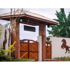 a horse is on the side of a white wall and wooden gates are in front of it