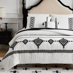 a black and white bed in a bedroom next to a night stand with two lamps