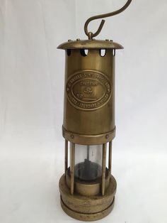 an old fashioned brass lantern with a light on it's side and a cord hanging from the top