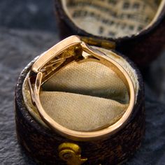 an open ring box sitting on top of a table next to a piece of cloth