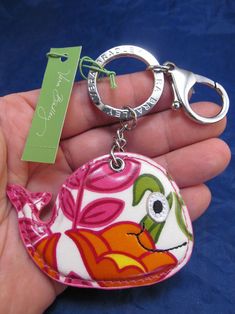 a hand holding a keychain with a bird on it's side and a name tag attached to it