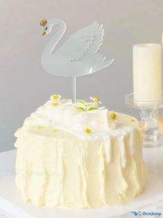 there is a cake that has been decorated with white frosting and a swan figurine on top