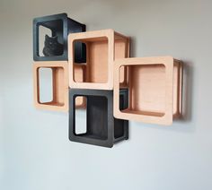 three wooden boxes are stacked on the wall and one has a black cat in it