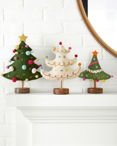 three wooden christmas trees sitting on top of a mantle