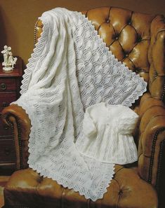 a white crocheted blanket sitting on top of a leather chair