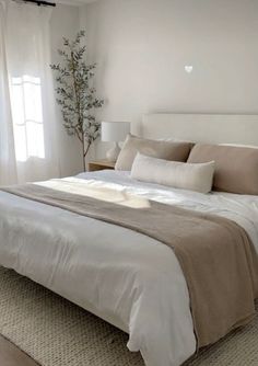 a bed with white sheets and pillows in a bedroom