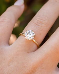 a woman's hand with a diamond ring on top of her finger, showing the center stone