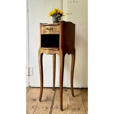 an old wooden table with a flower pot on top and a chalkboard in the drawer