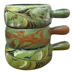 three ceramic mugs stacked on top of each other with leaves and flowers painted on them