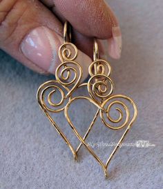 a pair of earrings that are being held in someone's hand with their fingers