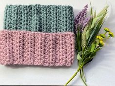 two crocheted items sitting on top of a table next to a bouquet of flowers