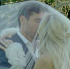 a bride and groom kissing under a veil