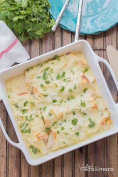 a casserole dish with chicken and cheese in it on a wooden table next to parsley