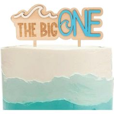 a wooden sign that says the big one sitting on top of a blue and white cake