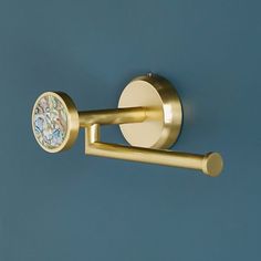 a close up of a gold toilet paper dispenser on a blue wall