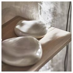 two white bowls sitting on top of a wooden shelf