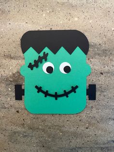 a paper cut out of a green monster with black hair and eyes on it's head