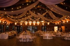 the inside of a banquet hall decorated with white linens and lights