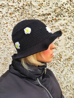 a woman wearing a black hat with white flowers on the brim and one ear