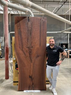 a man standing next to a large piece of wood