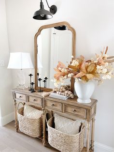 a white vase filled with flowers sitting on top of a wooden dresser next to a mirror