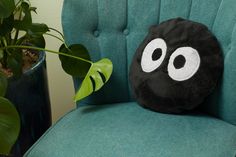 a green chair with a black and white pillow on it next to a potted plant