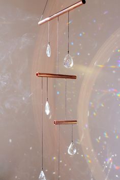 a wind chime hanging from the ceiling in front of a white wall with bubbles