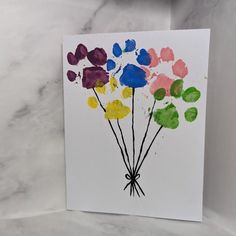 a card with flowers painted on it sitting on a marble countertop next to a white wall