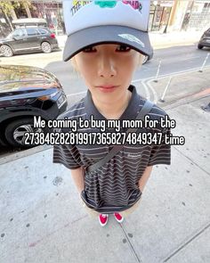 a young boy wearing a hat standing on the sidewalk