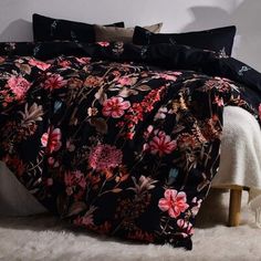 a bed covered in black and pink floral comforter sets on a white carpeted floor