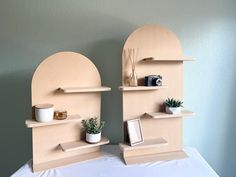 there are two shelves on the wall with plants and pictures in them, one is made out of cardboard